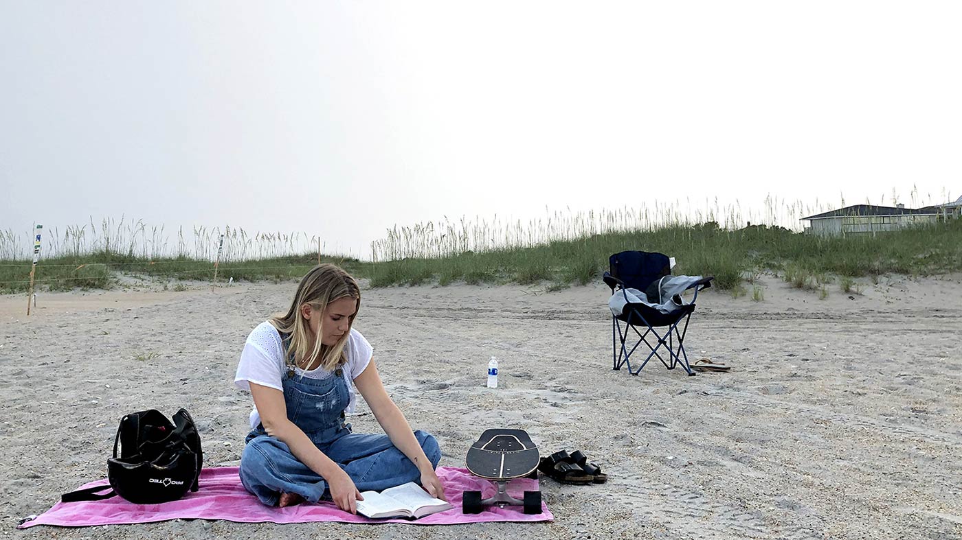 Laura Bratton, who has been sober for two and a half years, sits on the beach reading a book as she waits for a 12-step meeting to start in Wilmington, North Carolina.
